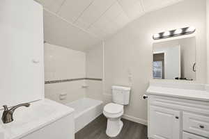 Full bath featuring vanity, dark wood-style flooring, bathtub / shower combination, and lofted ceiling