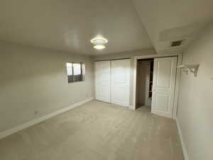 Unfurnished bedroom featuring light carpet and a closet