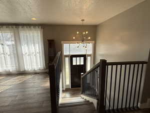 Foyer featuring a textured ceiling, a chandelier, and dark wood finished floors