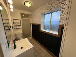 Full bathroom with vanity, a stall shower, tile patterned flooring, wallpapered walls, and a wainscoted wall