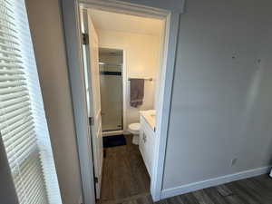 Bathroom featuring dark wood-style floors, vanity, and a stall shower