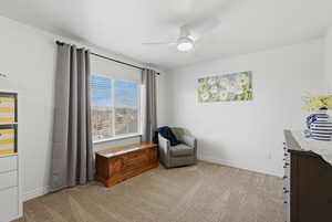 Living area featuring light colored carpet and ceiling fan