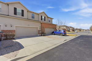 Traditional home featuring driveway, a residential view, stucco siding, a garage, and brick siding