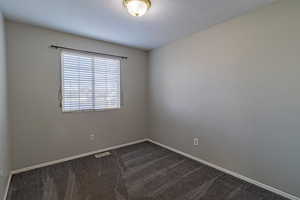 Unfurnished room featuring dark carpet and a textured ceiling