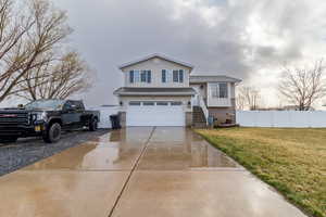 View of front facade with brick siding, driveway, and a garage