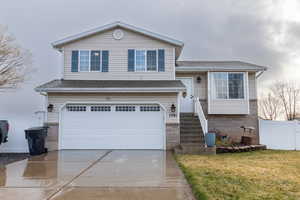 View of front of home with concrete driveway, a garage, roof with shingles, and brick siding