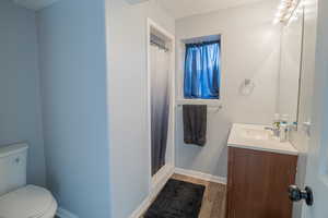 Full bathroom featuring a shower stall, vanity, and dark wood finished floors