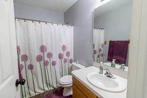 Full bathroom with vanity, shower / bathtub combination with curtain, and a textured ceiling