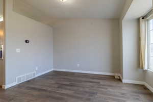 Spare room with vaulted ceiling and dark wood finished floors