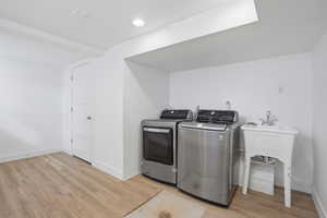 Downstairs Laundry area with light wood-style flooring and washer and dryer