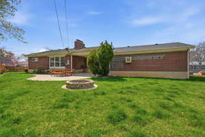 Back of property with a patio, brick siding, a fire pit, and a chimney