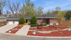 View of front of property featuring driveway, a garage, brick siding, and a chimney