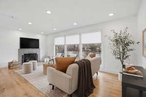 Living area featuring light wood finished floors, a fireplace, and recessed lighting