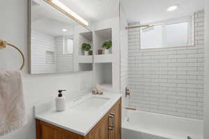 Downstairs Full bathroom featuring vanity, shower / bathtub combination, and a textured ceiling
