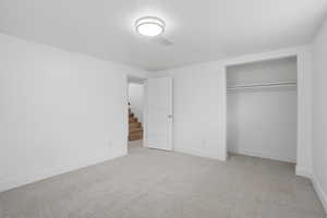 Basement bedroom with light colored carpet and a closet