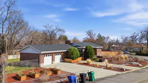 Single story home with a fenced front yard, brick siding, concrete driveway, a vegetable garden, and an attached garage