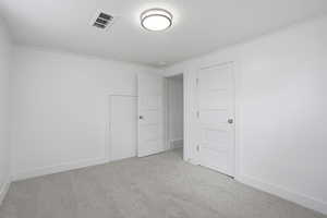 Downstairs bedroom with light colored carpet and crown molding