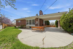 Rear view of property with a patio, a chimney, and brick siding