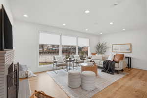 Living area featuring light wood-style flooring, a brick fireplace, and recessed lighting