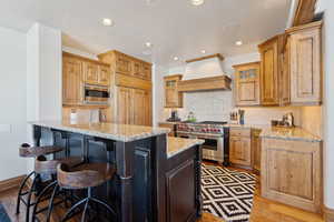 Kitchen featuring a breakfast bar, a peninsula, stainless steel appliances, light stone countertops, and backsplash