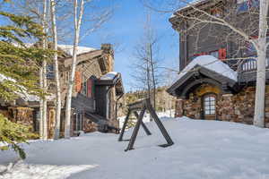 View of snow covered exterior with stone siding and a chimney