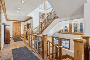 Foyer featuring healthy amount of natural light, recessed lighting, stone tile flooring, crown molding, and a high ceiling