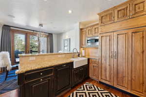Kitchen featuring a peninsula, light stone counters, dark wood-type flooring, stainless steel microwave, and a textured ceiling