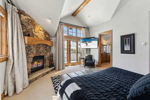 Bedroom with light colored carpet, access to outside, a fireplace, and ensuite bathroom