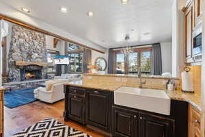 Kitchen with a stone fireplace, light stone counters, light wood-style flooring, open floor plan, and a peninsula