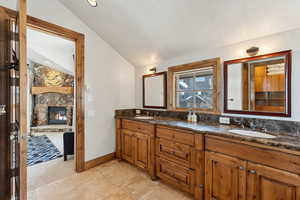 Bathroom with vaulted ceiling, double vanity, and a fireplace