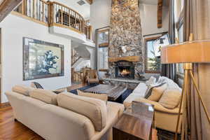 Living area featuring a stone fireplace, a high ceiling, and wood finished floors