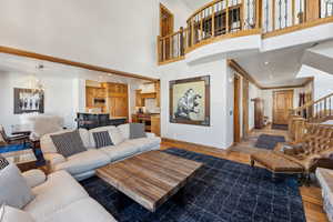 Living room featuring dark wood-style floors, hanging lights, and a high ceiling