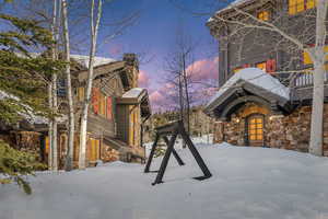 Snow covered property featuring stone siding and a chimney