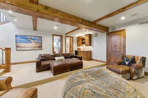 Living room featuring recessed lighting, light colored carpet, bar with sink, and beamed ceiling