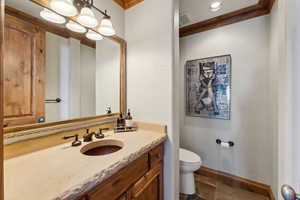 Bathroom with stone tile flooring, vanity, crown molding, and a textured wall