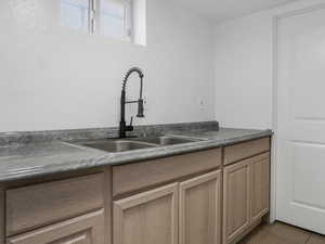 Dark countertops, light tile patterned floors, and light wood finish cabinetry