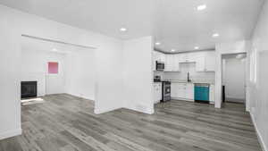 Kitchen featuring stainless steel appliances, white cabinetry, open floor plan, light countertops, and recessed lighting
