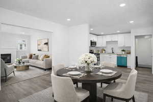 Dining area featuring dark wood-type flooring, recessed lighting, and a brick fireplace. Kitchen with new appliances.