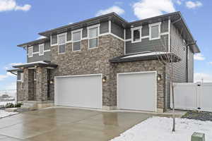 View of front of property with a garage, driveway, and stone siding