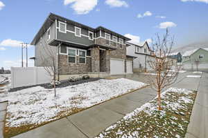 View of front of home featuring stone siding, concrete driveway, and an attached garage