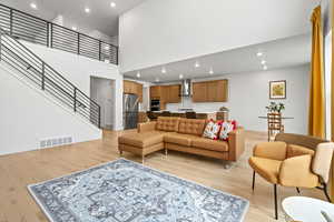 Living area with light LVP wood  floors, recessed lighting, and a high ceiling