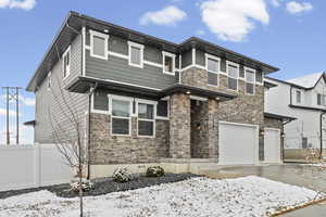 View of front of home featuring stone siding, a garage, and concrete driveway