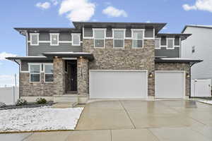 Exterior of home with stone siding, concrete driveway, a garage, and a gate
