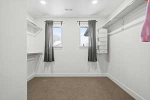 Walk in closet featuring windows and built in shelving.
