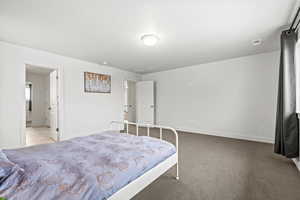 Bedroom with light colored carpet, ensuite, and baseboards