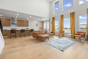 Living area featuring light LVP wood  floors, recessed lighting, and a high ceiling