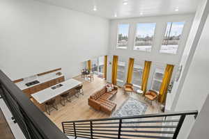 View from loft area of living room with light LVP wood flooring, a high ceiling, and recessed lighting