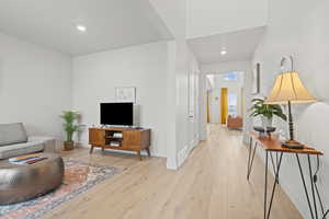 Formal living room off of entry featuring light wood LVP floors and recessed lighting
