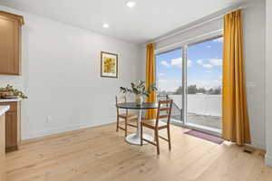 Dining room with light LVP wood flooring, large sliding glass window, and recessed lighting