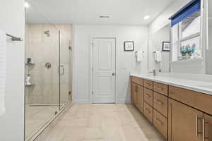 Full bathroom featuring double vanity, a glass stall shower, and recessed lighting